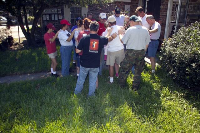 Team members praying in the front yard of Roger and Ellen's home 