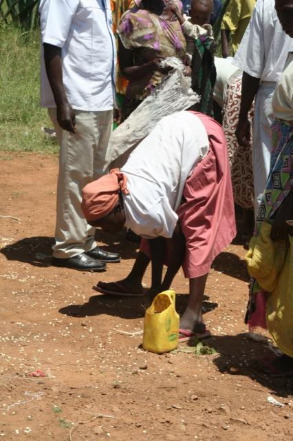 An old woman (ajuza) picks up the last of the corn that has spilled on the ground to take home for her family 