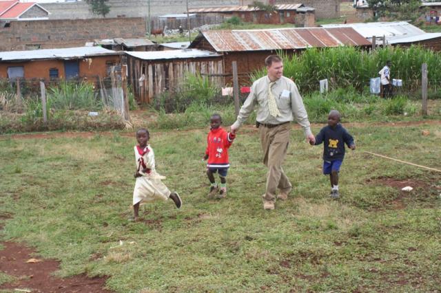 Some of the neighborhood kids help David Campbell out measuring a possible for the Eldoret orphanage 