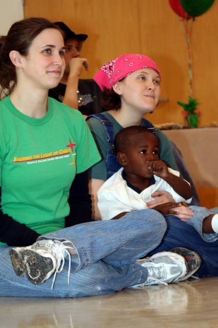 Two college girls from a relief team from Texas care for one of the kids at the party. 